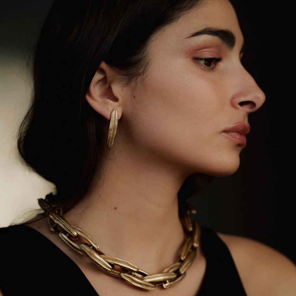 Woman wearing a gold chain necklace and hoop earrings  Phoenix Earrings Sterling Silver Ariana Boussard-Reifel