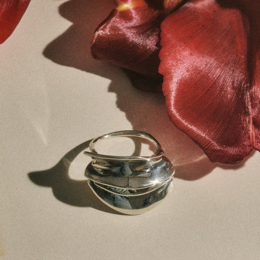 Silver ring on a beige surface with a red flower  Ranunculus Ring Ariana Boussard-Reifel