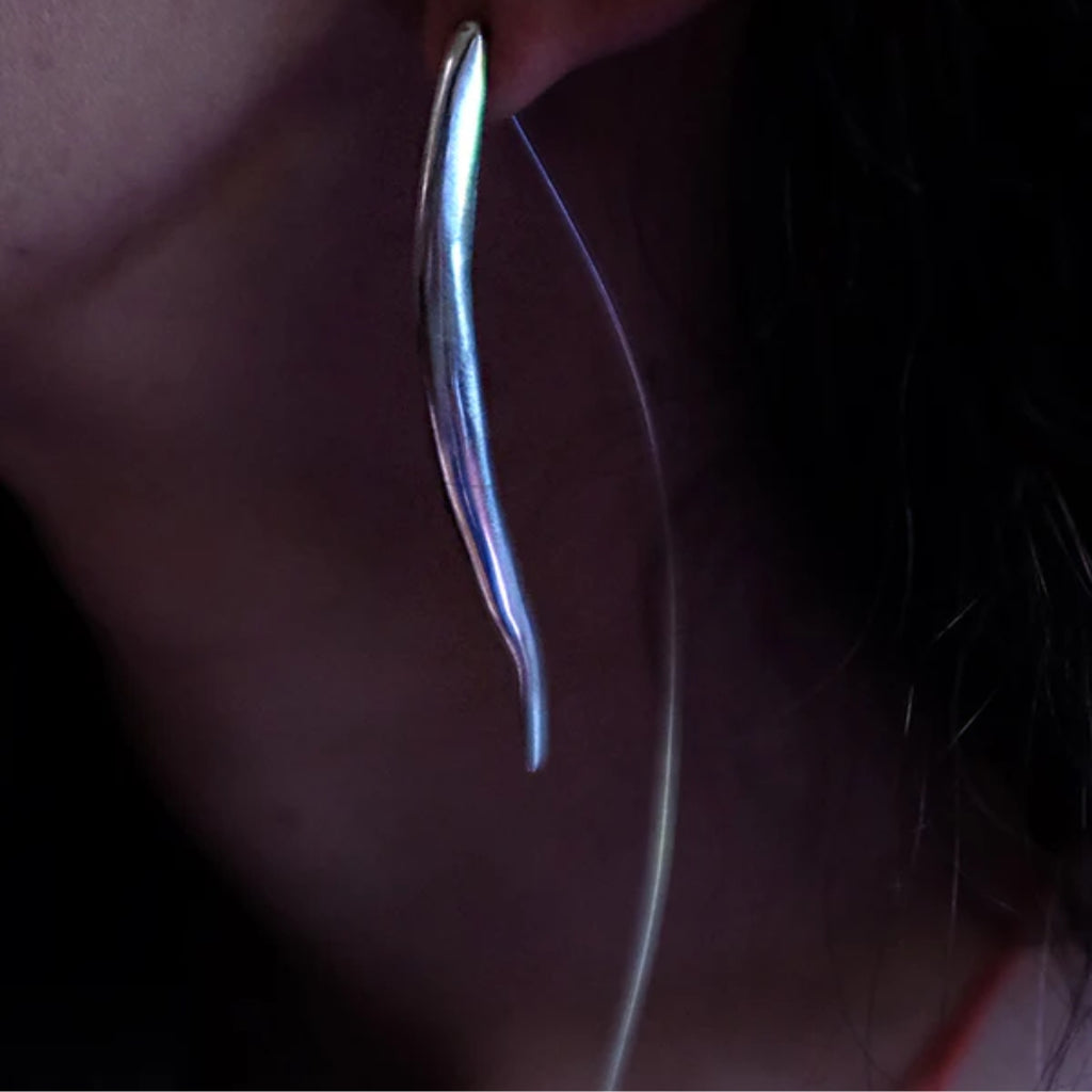 Close-up of a metallic earring on a dark background