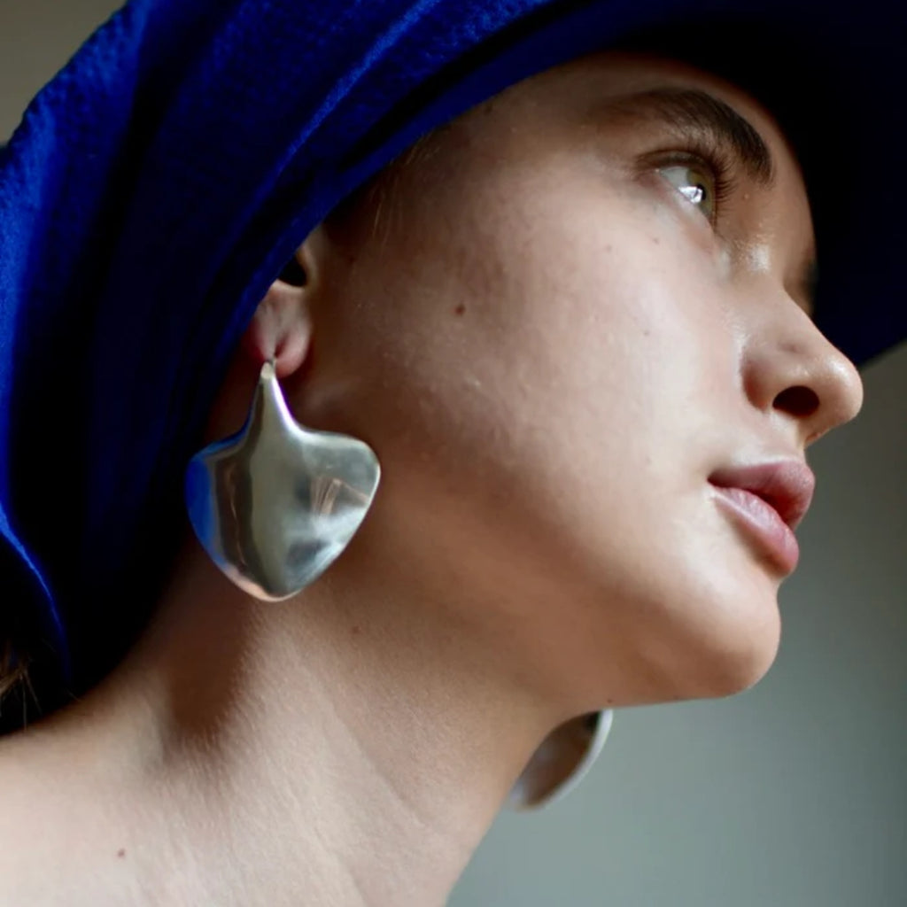 Close-up of a person wearing a blue headscarf and silver earrings.