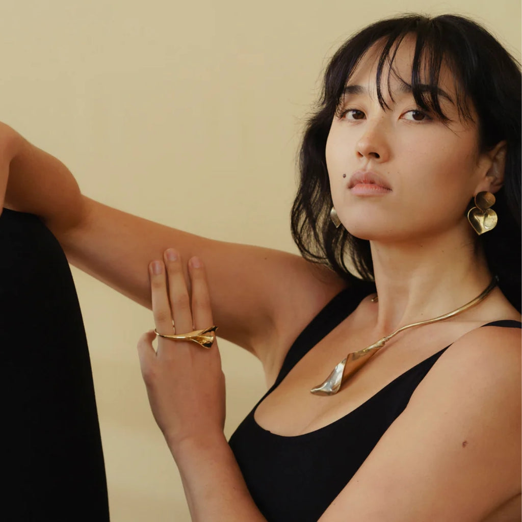 Woman wearing gold jewelry against a beige background