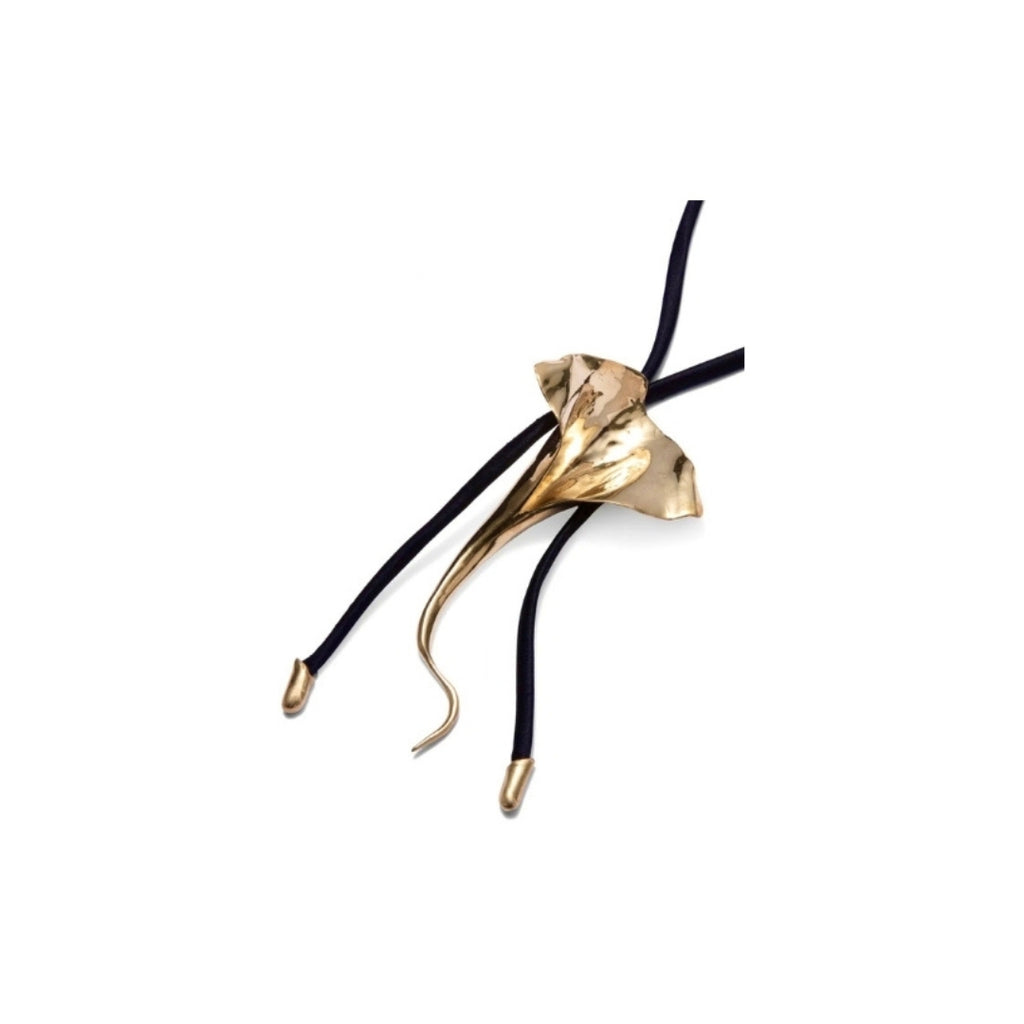 Close-up of a gold floral pendant on a black cord necklace.