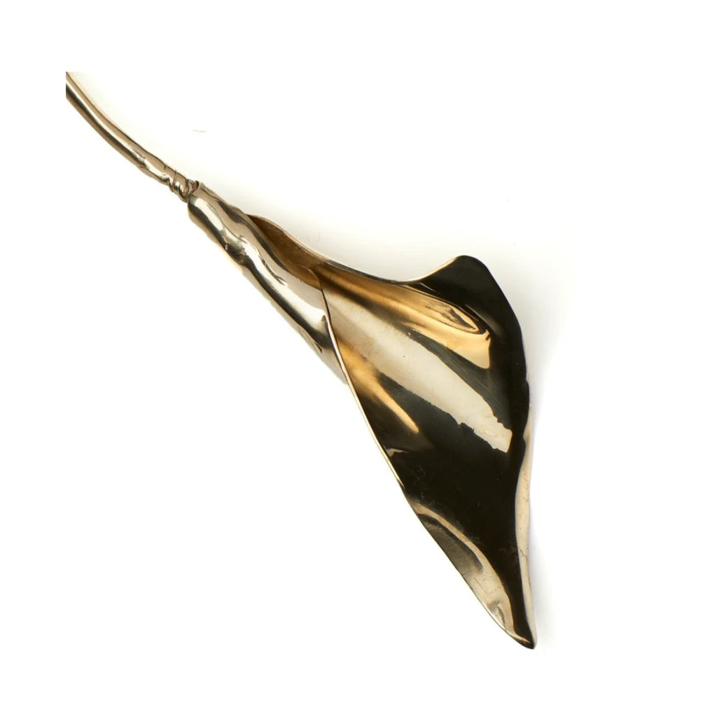 A model wearing a gold calla lily necklace and matching earrings, exuding confidence against a soft background.