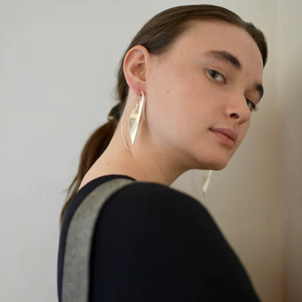 Woman wearing large hoop earrings with a neutral background