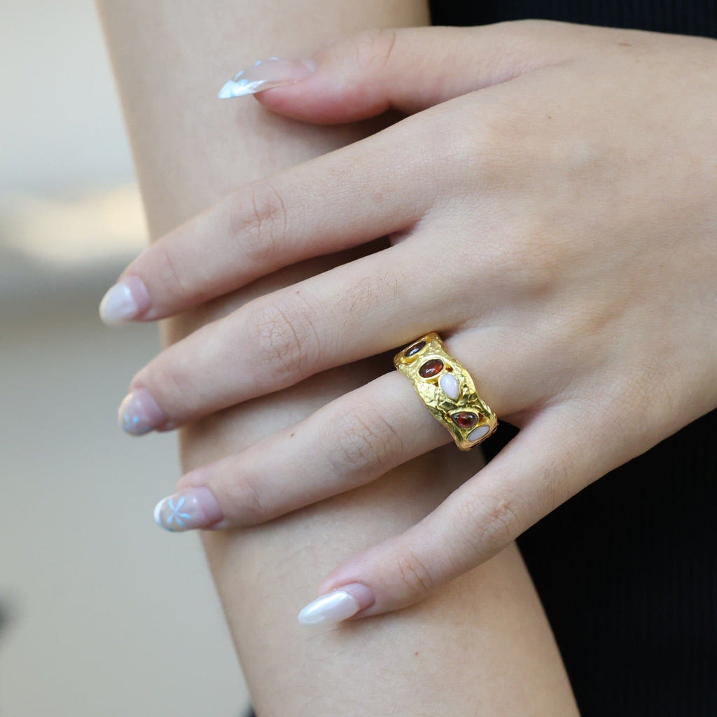 Hand wearing a gold ring on a blurred background