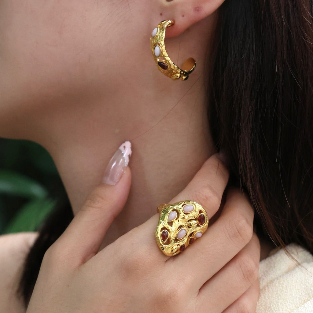 Close-up of a person wearing gold hoop earrings and a matching ring.