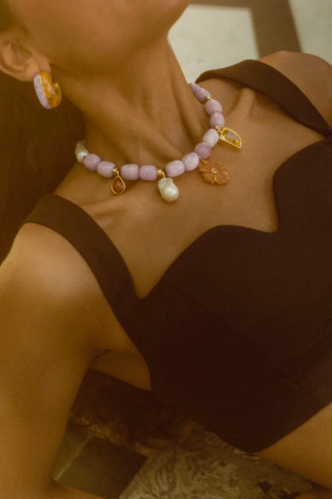 Step into a world of pastel perfection with the exquisite Basque Necklace in Lavender by Lizzie Fortunato featuring a stunning blend of kunzite nugget and freshwater pearl beads, and an enchanting collection of charms including a hand-carved peach aventurine flower set with a pink amethyst stone.