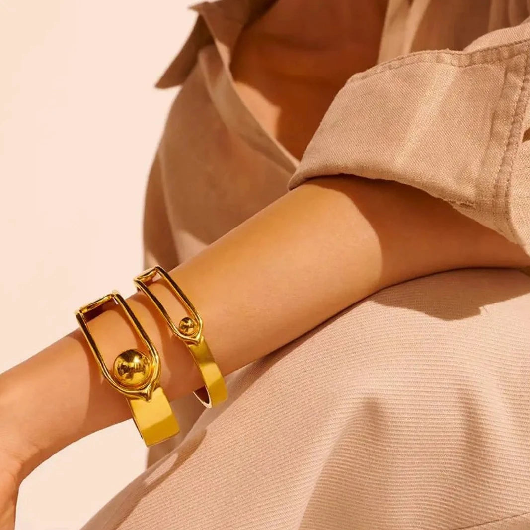 The Boucle GM Bracelet by Goossens Paris is a sleek and modern bracelet made from brass soaked in a 24-carat gold bath, featuring the distinctive House of Goossens clasp and a light and pleasant design that can be mixed and matched for a unique effect.