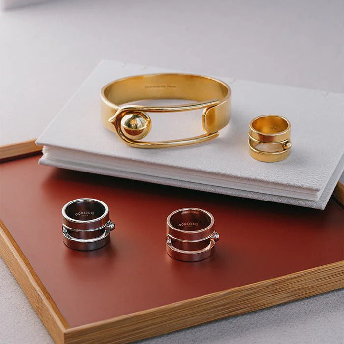 The Boucle Large Ring Yellow Gold by Goossens Paris is a sleek and modern brass ring soaked in a 24-carat gold bath, featuring the distinctive House of Goossens clasp and a light and pleasant design that can be mixed and matched for a unique effect.