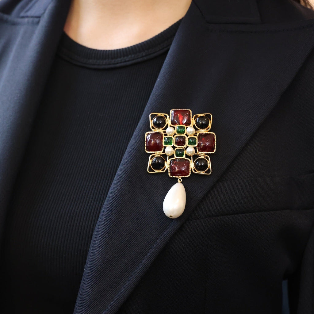 Jeweled brooch with red and green gemstones on a black blazer