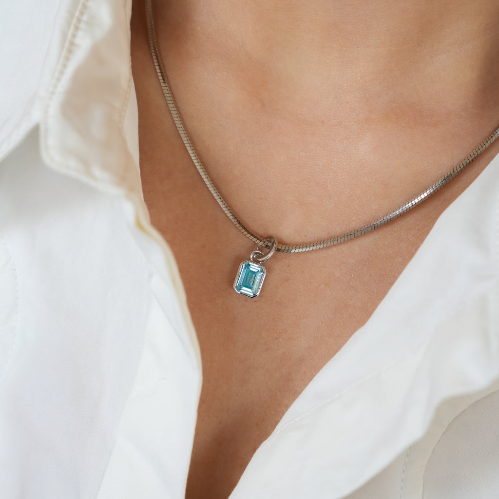 Necklace with a blue gemstone pendant worn by a person in a white shirt. Anniversary Limited Edition Gift Set - Timeless Anniversary Necklace Blue Pendant by LOUVE