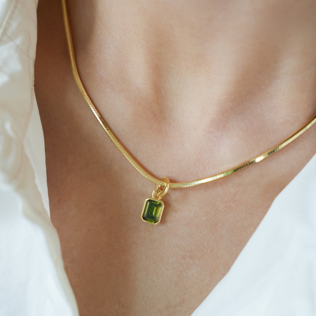 Gold necklace with a green pendant on a person wearing a white shirt. Anniversary Limited Edition Gift Set - Timeless Anniversary Necklace Green Pendant by LOUVE