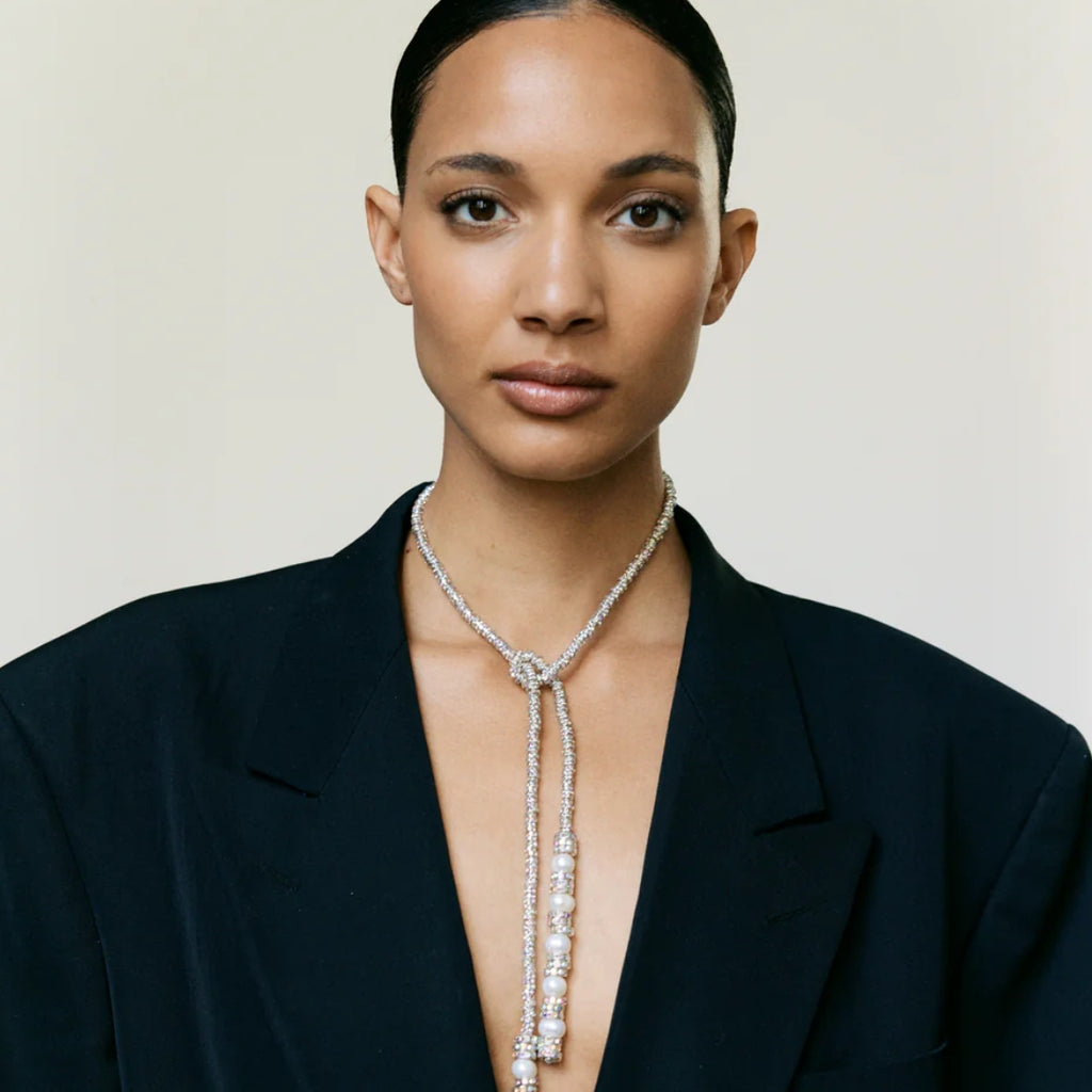 Woman wearing a long necklace against a neutral background