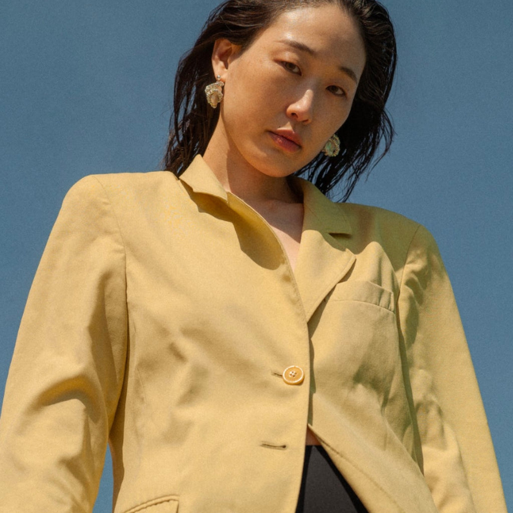Woman wearing a beige jacket against a clear blue sky