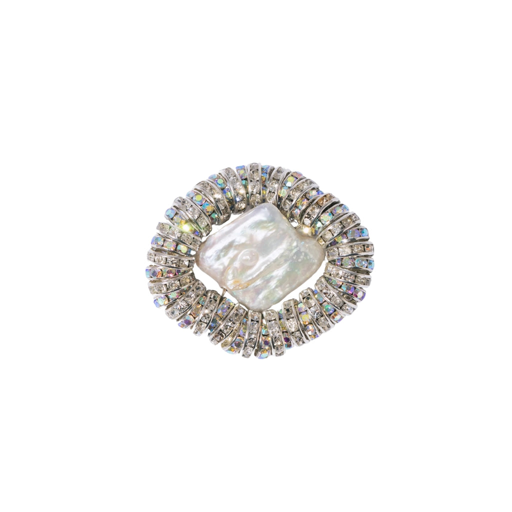 Brooch with a central pearl surrounded by rhinestones on a white background