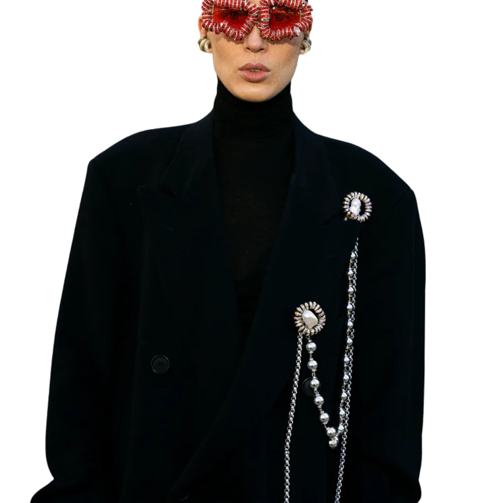 Person wearing a black coat with decorative elements on a white background