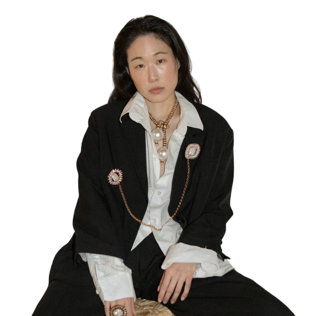 Woman wearing a black blazer with decorative brooches on a white background