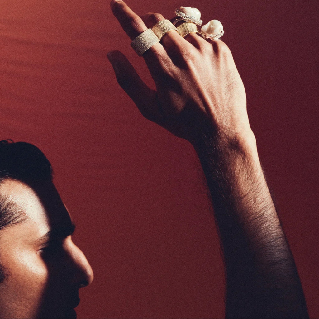 Hand with multiple rings raised against a red background