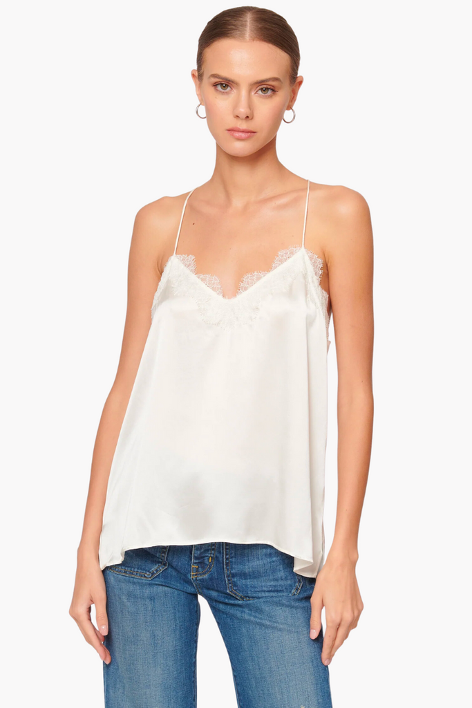 The Racer Charmeuse Cami by Cami NYC is a versatile and luxurious wardrobe essential made from silk sandwash charmeuse, featuring a delicate V-neckline with feminine French lace trimming and a relaxed fitting bodice, perfect for any occasion and available in timeless white.