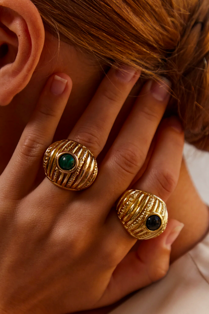 The Reef Ring from Paola Sighinolfi is a handcrafted, 18kt gold-plated organic ring inspired by coral gardens and featuring a black stone that exudes regal elegance and tranquility, making it a timeless and elegant accessory perfect for any formal occasion.